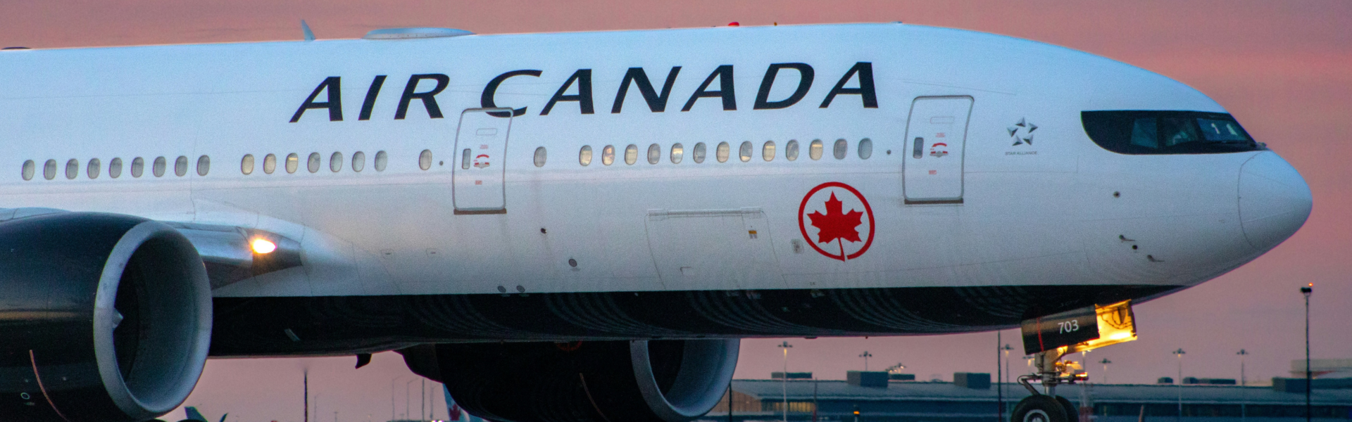 an air canada plane on a runway in front of a setting sun