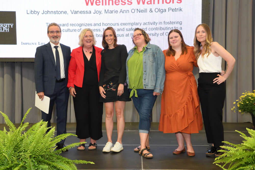 The College of Arts Wellness Warriors pose with Rene Van Acker as they're presented with their staff award.