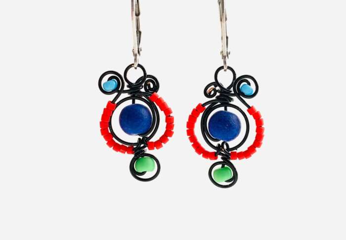 A pair of earrings. The earrings are black wire with beads - there's a large blue bead in the middle surrounded by small orange beads, with a medium green bead at the bottom and a medium light-blue blue bead at the top.