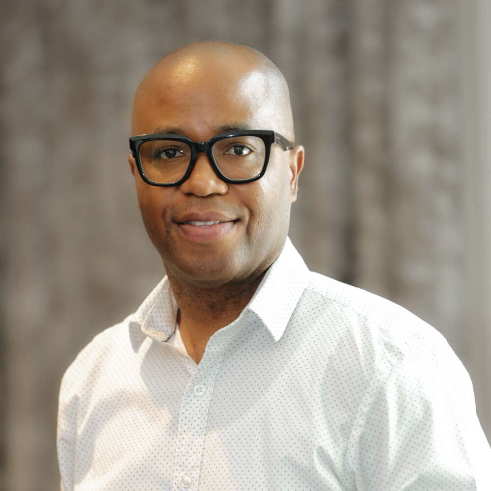 a man in glasses and a white shirt poses for a headshot