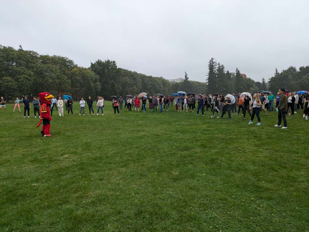 The crowd follows warm-up instructions from Gryph on Johnston Green.