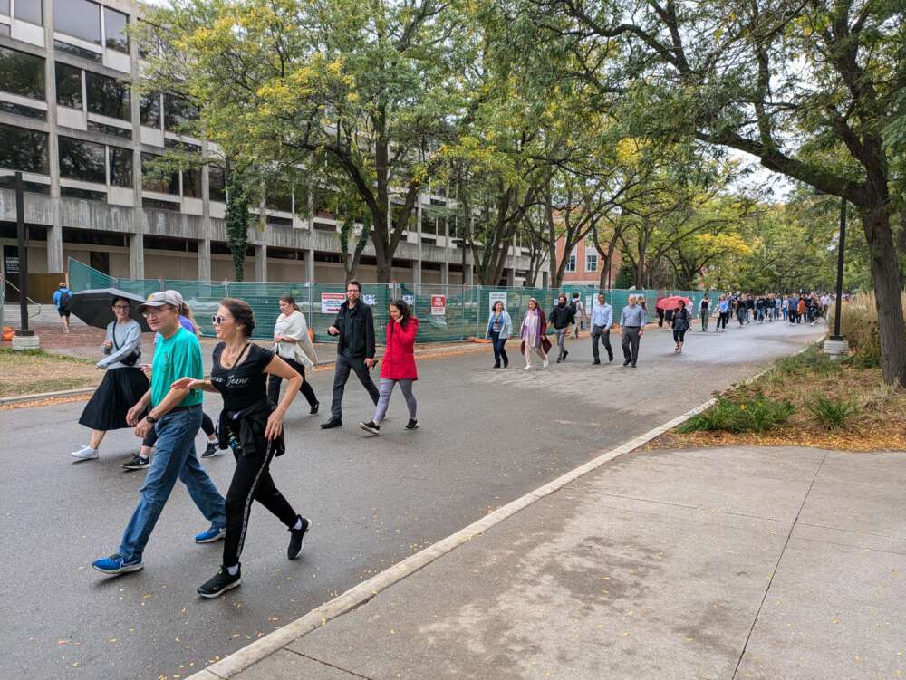 Faculty and staff walk down a path on campus.