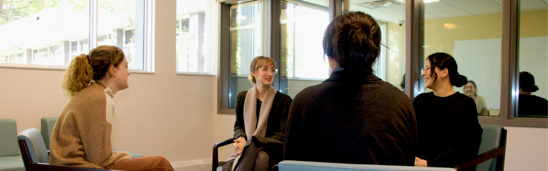 Four students sit facing each other in a brightly lit therapy office, engaged in conversation