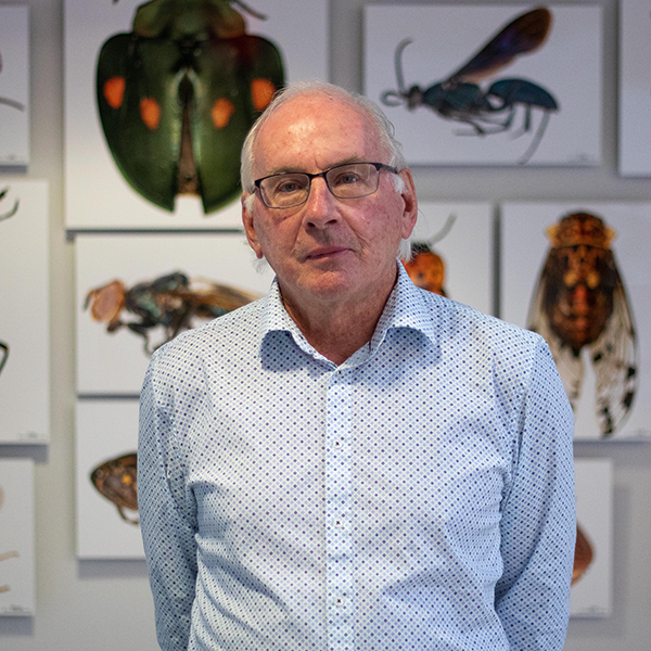 Dr. Paul Hebert poses for a portrait in the atrium of the Centre for Biodiversity Genomics at the University of Guelph with canvas prints of magnified photos of insects hanging on the wall behind him