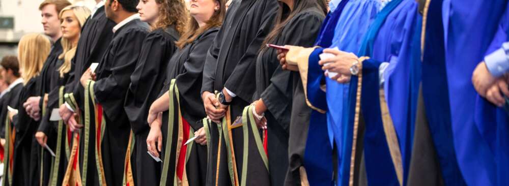The hands of several graduands in robes