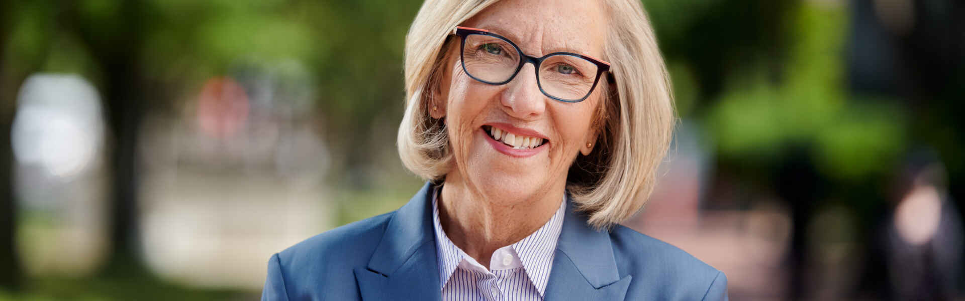 Headshot of Dr. Charlotte Yates outside on University campus, wearing a blazer and collared shirt.