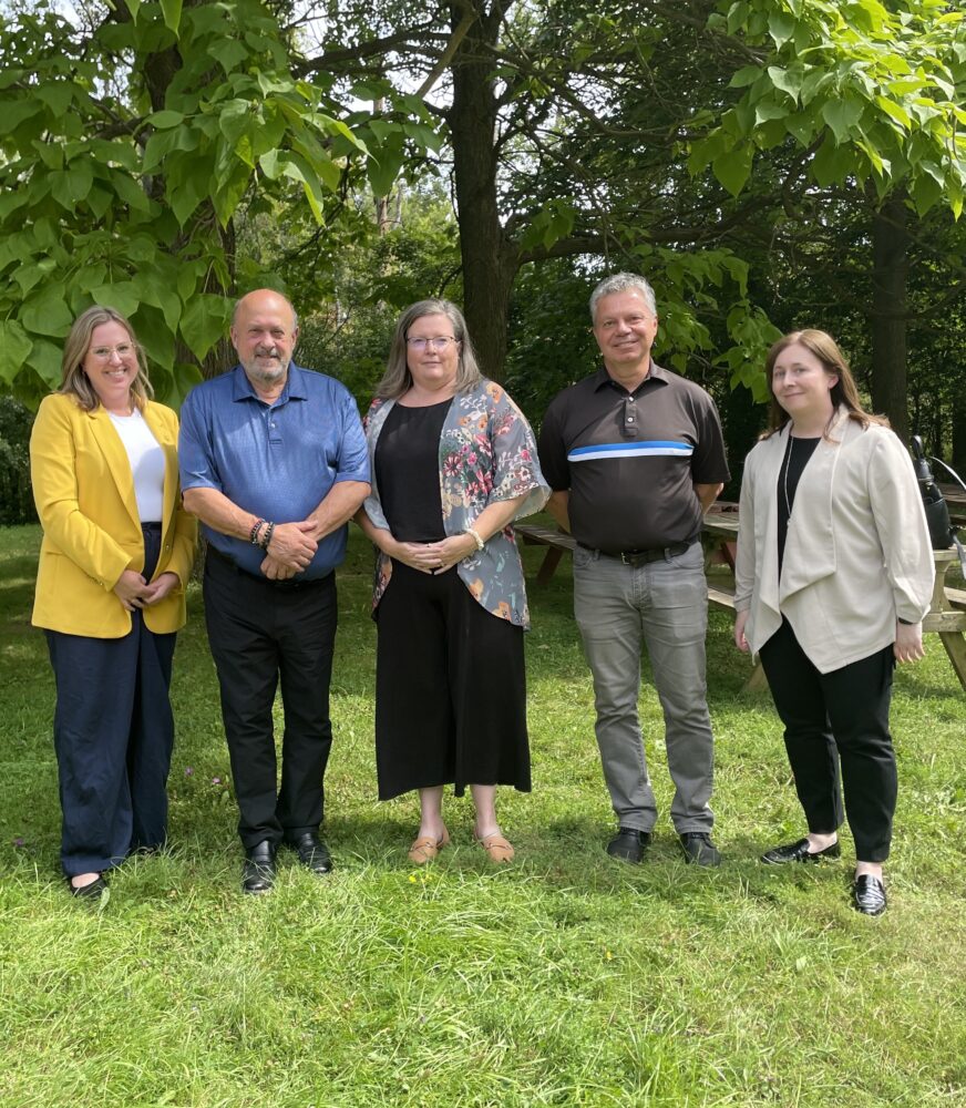 A group of five people from U of G and Minister Tibollo's office stand together outdoors posing for a group photo.