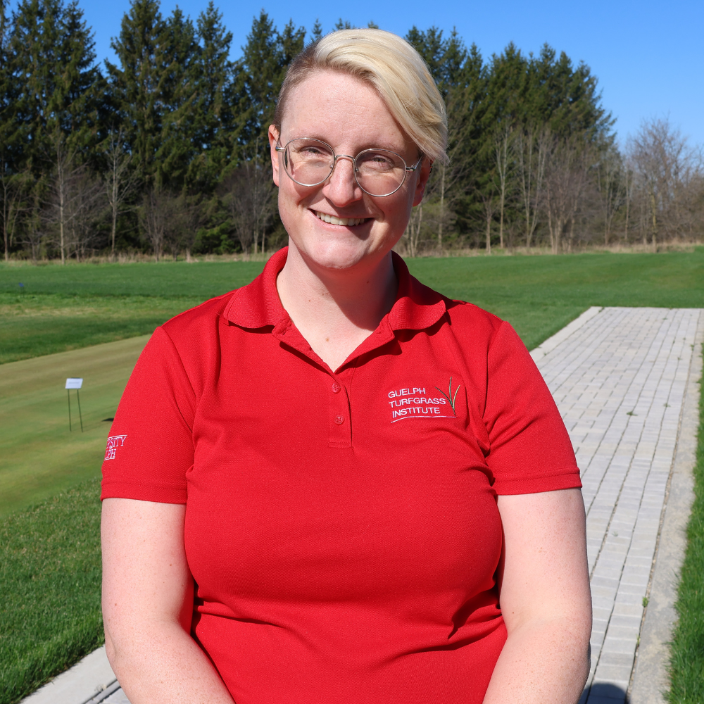 a blonde woman with glasses in a red polo shirt poses for a headshot