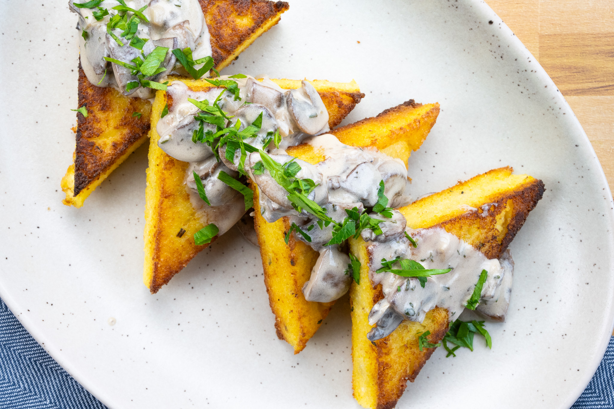 Four sandwiches on a plate, covered in goat cheese polenta with mushroom cream sauce