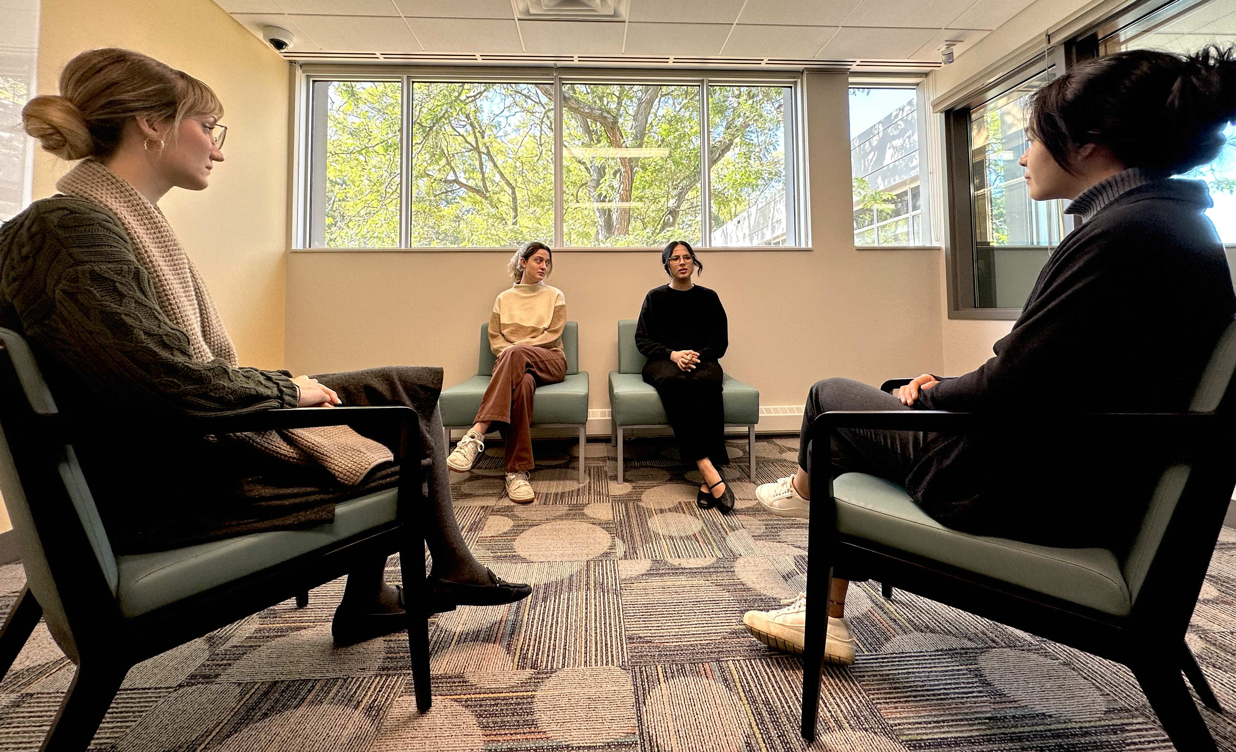 Two students face two other students seated on a couch in a mock counselling session