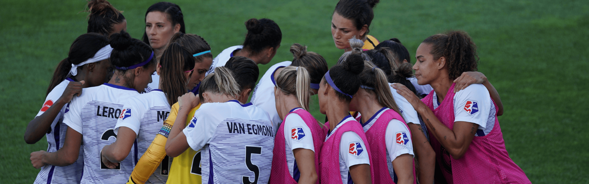 Athletes huddle in a team huddle on a sports field