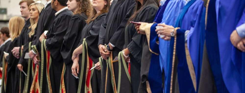 students in blue and black grad gowns at a convocation ceremony