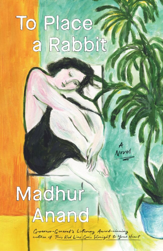 Cover of the novel To Place a Rabbit by Madhur Anand. The artwork is a stylized painting of a woman with pale skin and short dark hair wearing a black slip dress. She sits curled up with her arms around her knees, resting her cheek on them, her eyes closed as if in thought or sleep. Behind her is a tall green potted plant with long leaves against a cool teal background. The left side of the image has bold orange and yellow vertical color blocks. The title appears in large white text across the top: To Place a Rabbit. Below, the author’s name is written in white: Madhur Anand. A handwritten note in yellow reads: “Governor General’s Literary Award-winning author of This Red Line Goes Straight to Your Heart.” The words “A Novel” are written near the woman’s feet.