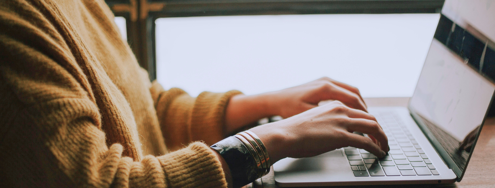 Person sitting at a computer, their hands resting on the keyboard
