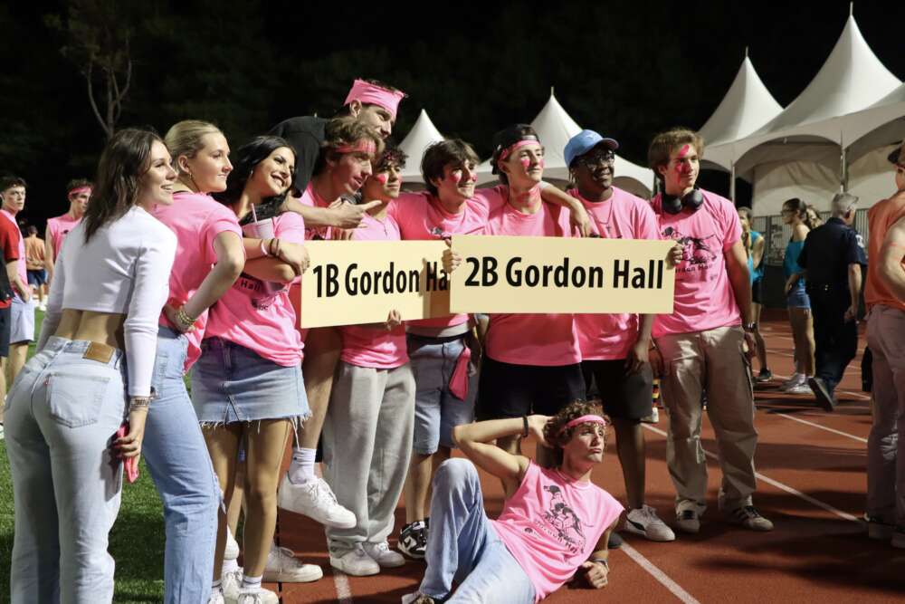 students in pink shirts pose on the track with signs reading "1b gordon hall" and "2b gordon hall"