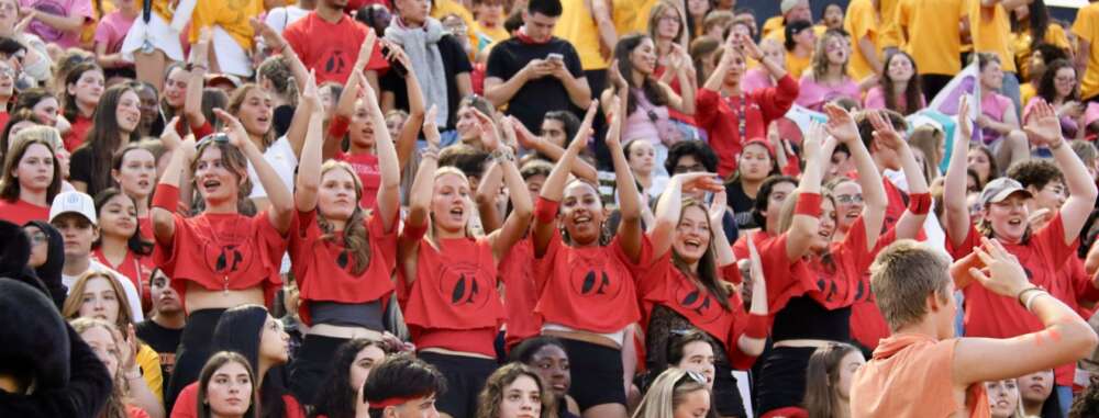 students dressed in red shirts pose in a crowd in the bleachers