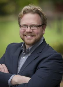 Headshot of Dr. Michael Steel, dressed in a suit jacket and button up shirt, smiling.