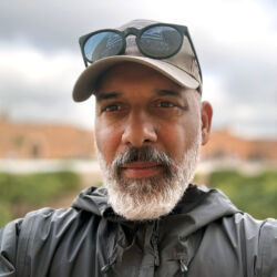 a person in a ballcap smiles for a photo outside