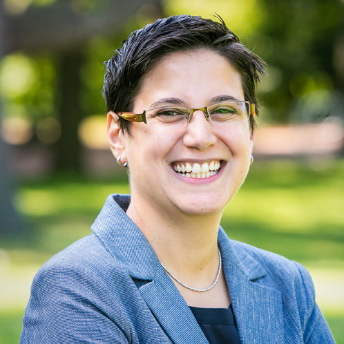 headshot of a person smiling for a portrait standing outside