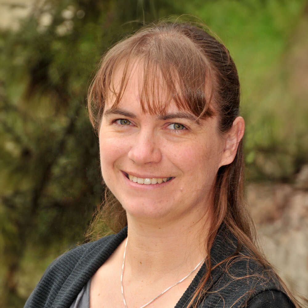 a headshot of a person smiling while posing for a portrait outside