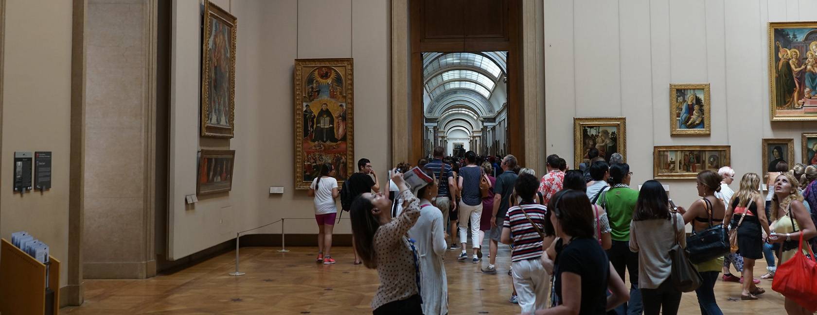 dozens of visitors look at paintings in a louvre gallery room
