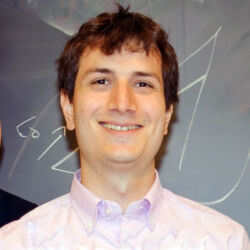 Dr. Mihai Nica poses for a photo in front of a blackboard