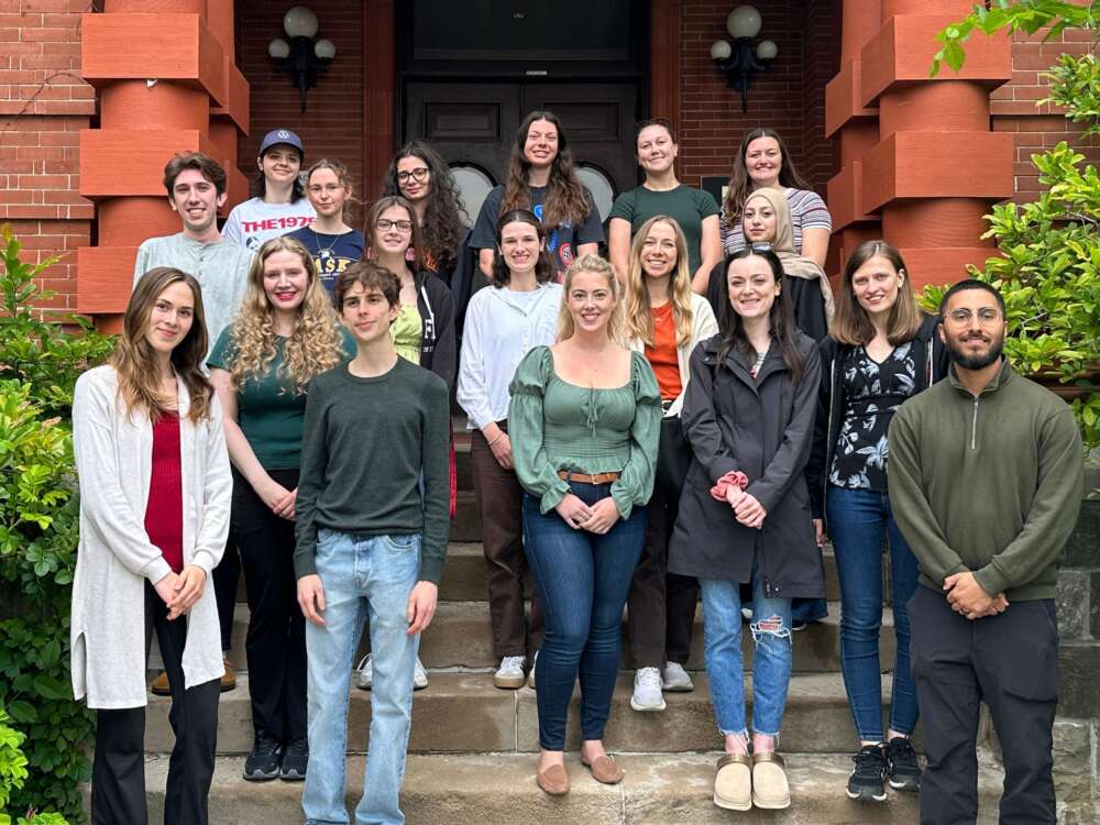 a group of students pose on stone steps in front of a red brick building