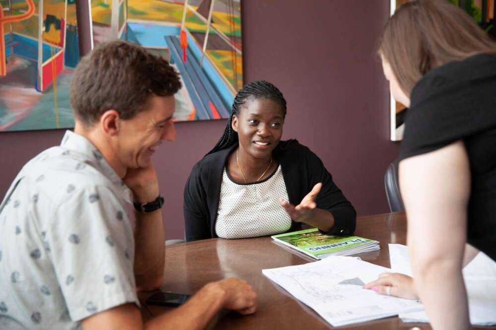 Three students discuss project over table 