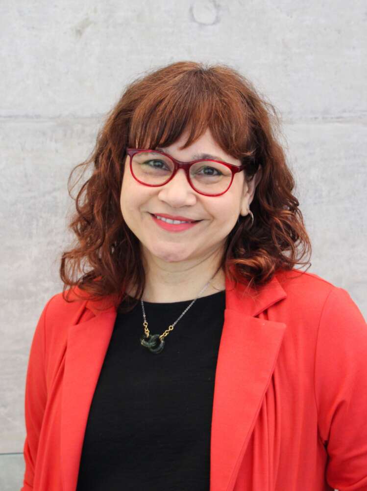 Person with red hair and glasses smiles for headshot