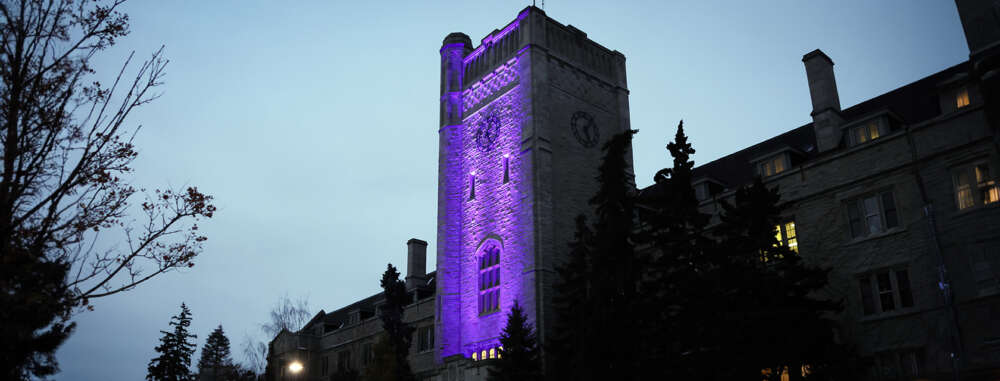 The tower of Johnston Hall on the U of G campus is shown in the evening, lit in purple