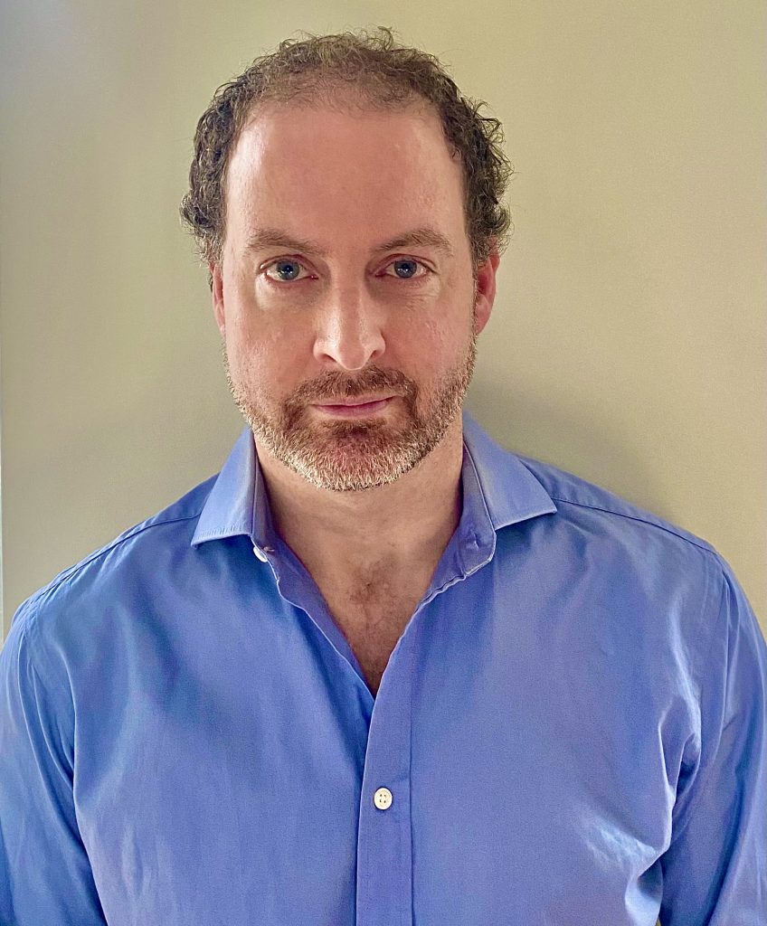 Dr. Kevin James posed for headshot against beige wall