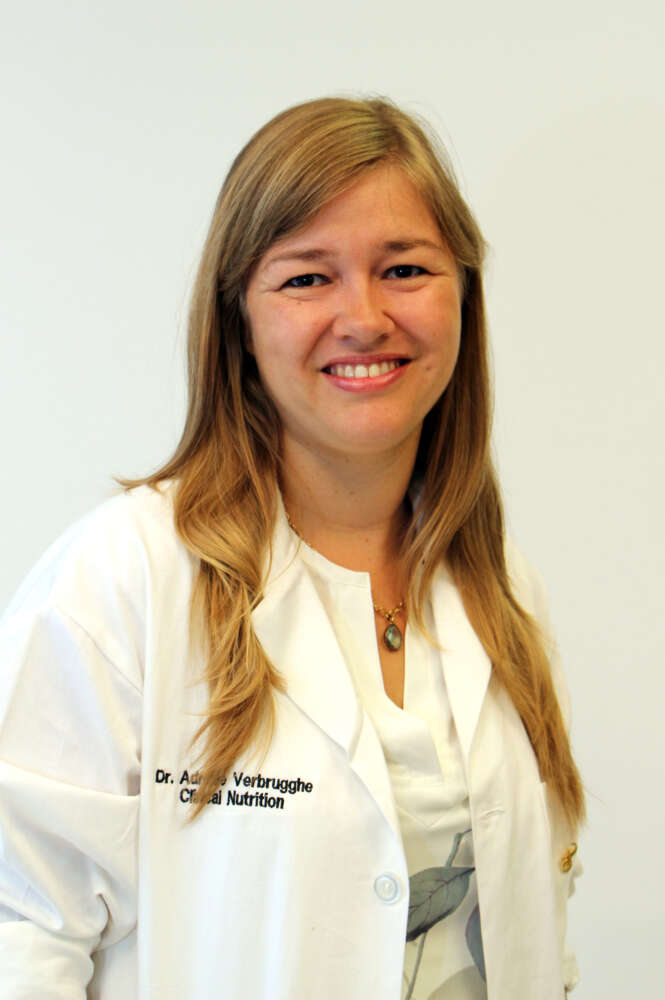 a person with blonde hair in a lab coat poses for a headshot