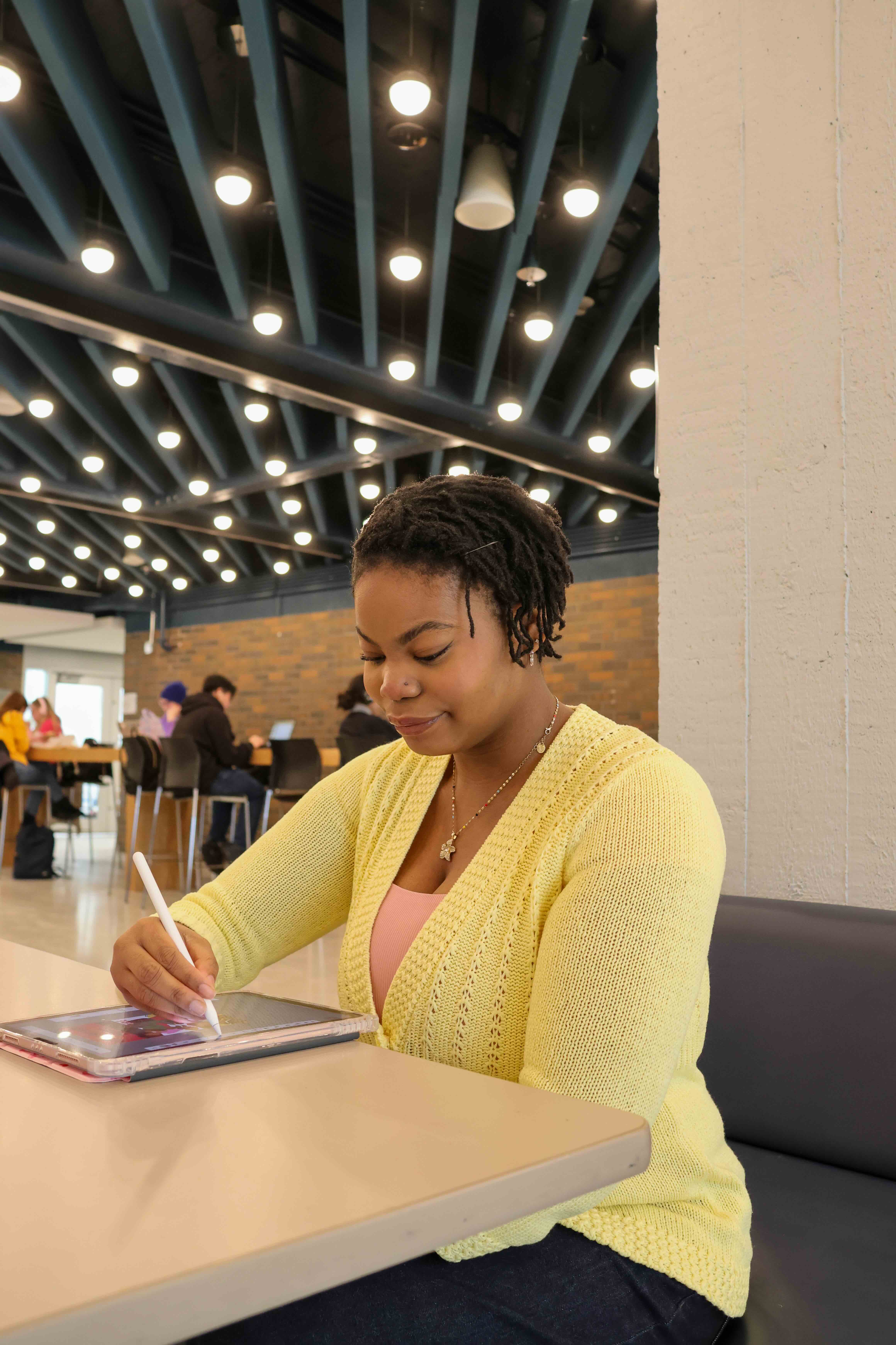 Student draws on a tablet in a cafeteria space