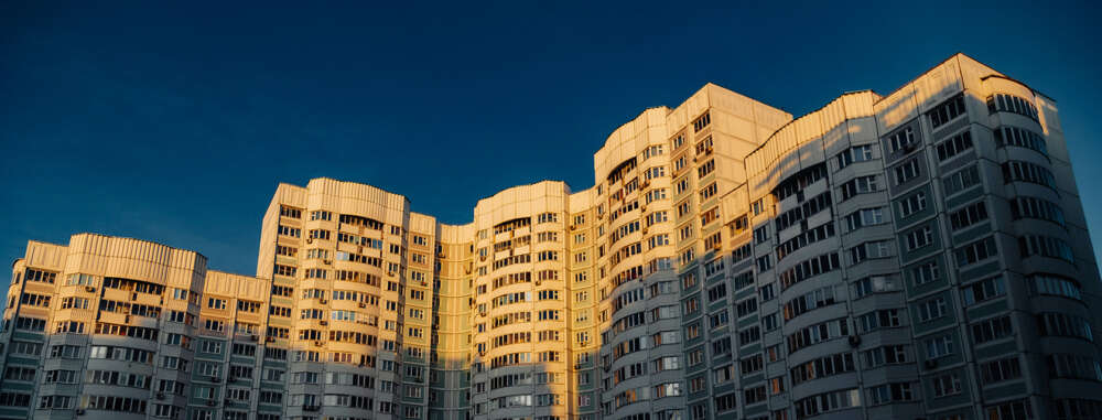 The tops of a large condo tower against a blue sky