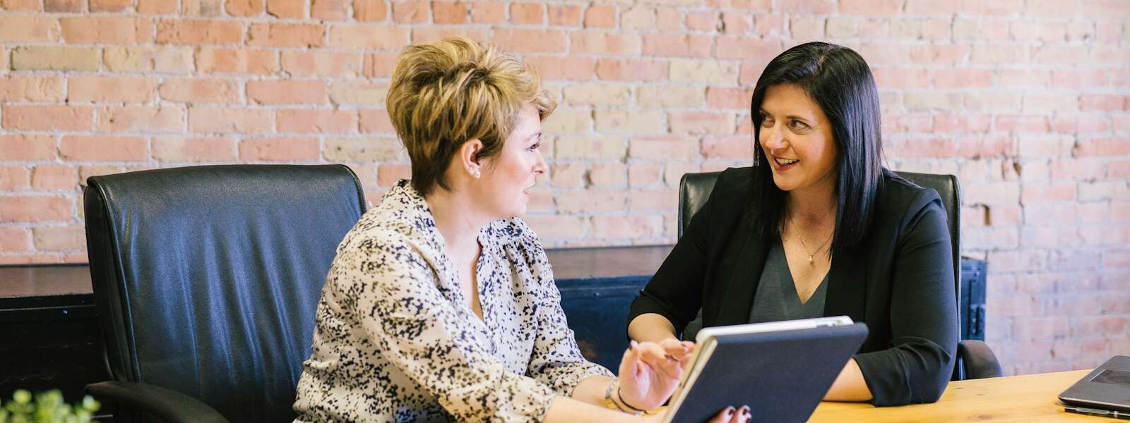 two women sitting on leather chairs in front of table