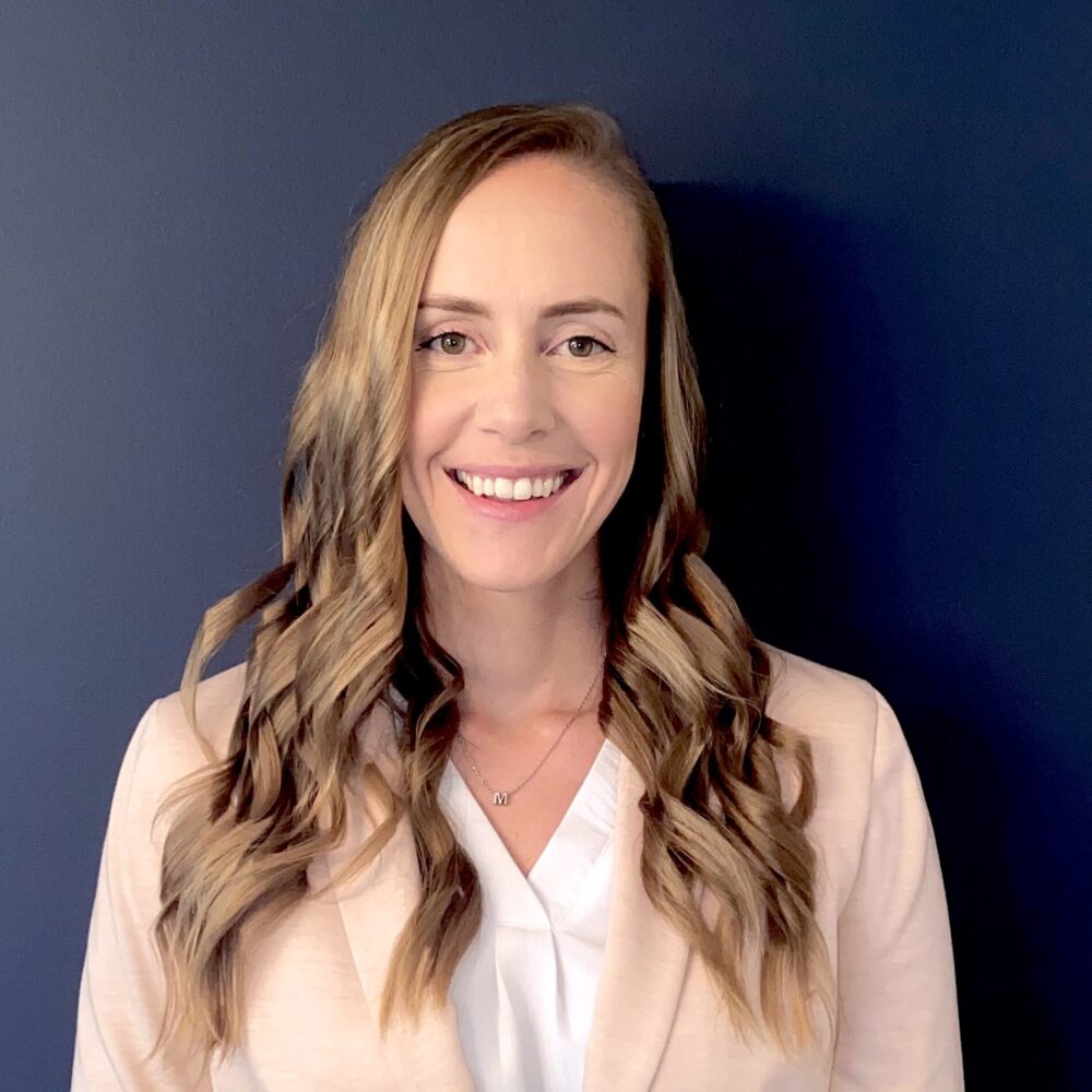 Dr. Melissa Walker poses for headshot against blue wall