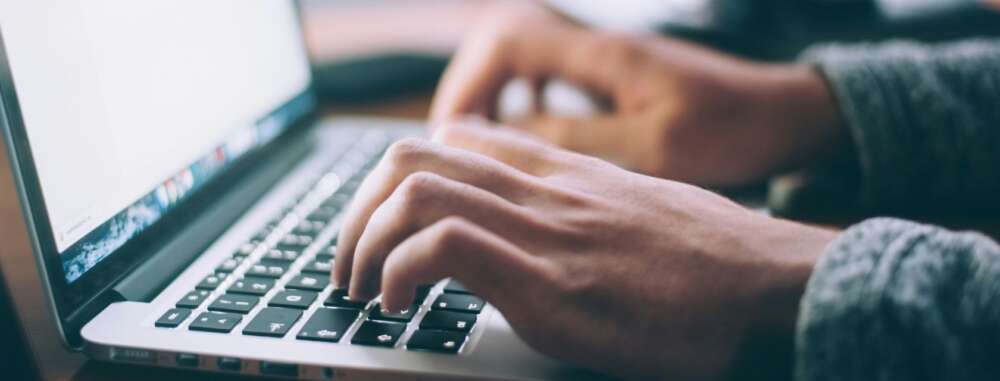 Close-up of hands typing on a silver Macbook
