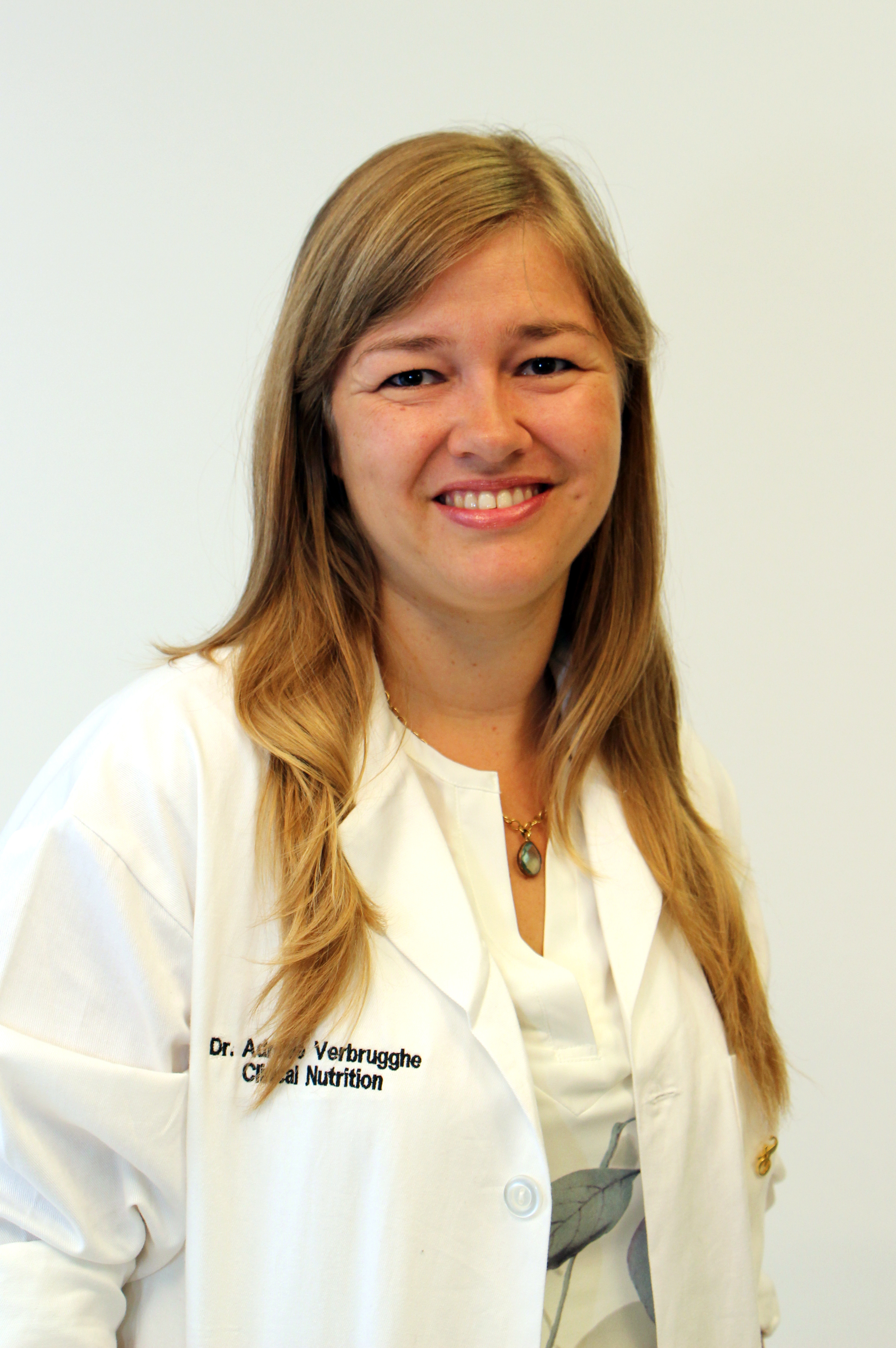 a person with blonde hair in a lab coat poses for a headshot