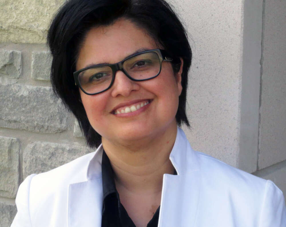 Dr. Rozita Dara smiles for a photo in front a stone brick building