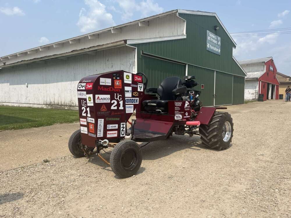 a red tractor with bumper stickers in front of a green barn