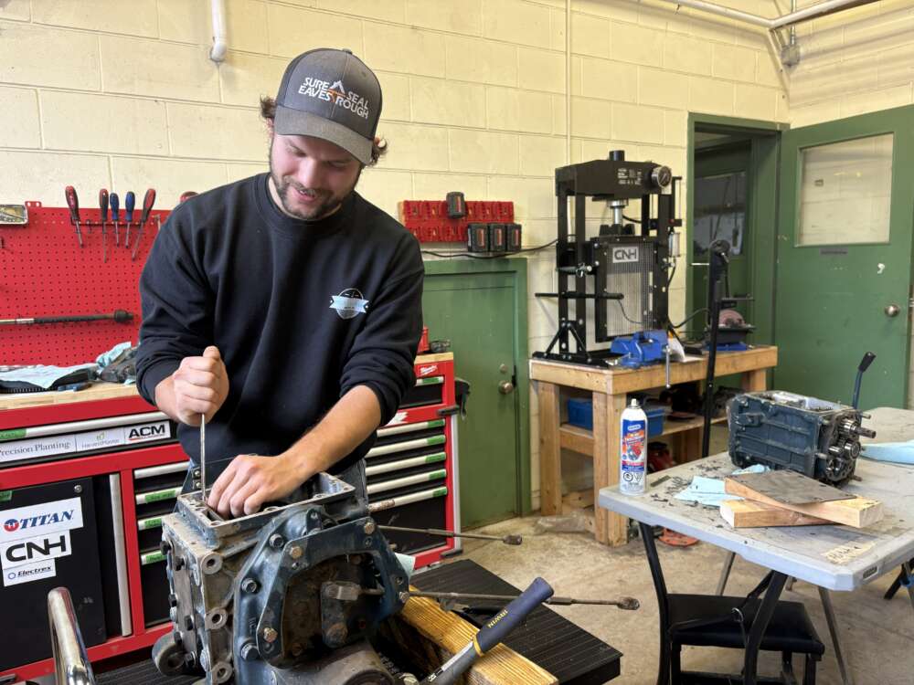 person in a sweatshirt and hat works on a piece of machinery