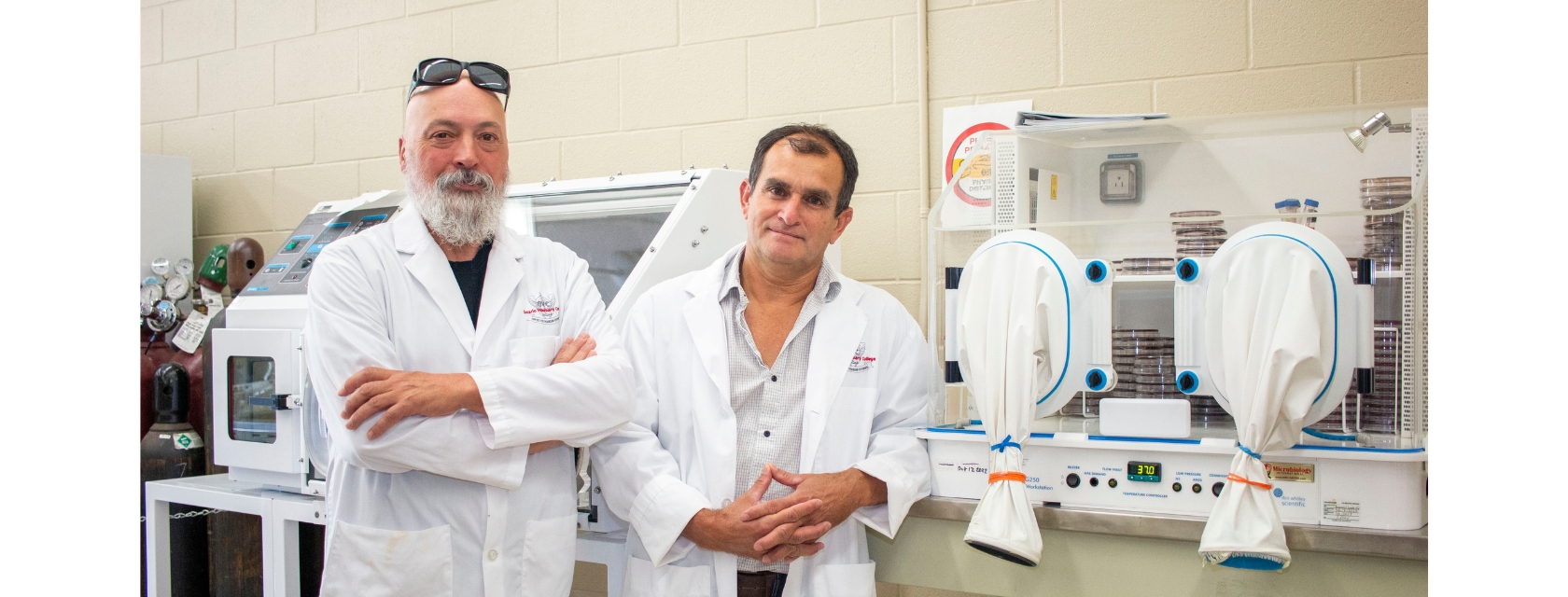 Two researchers pose in front of laboratory equipment