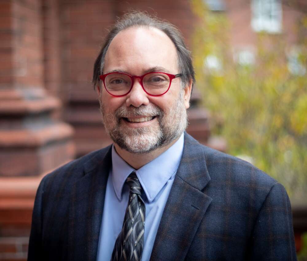Dr. Byron Sheldrick wears a suit and smiles at the camera