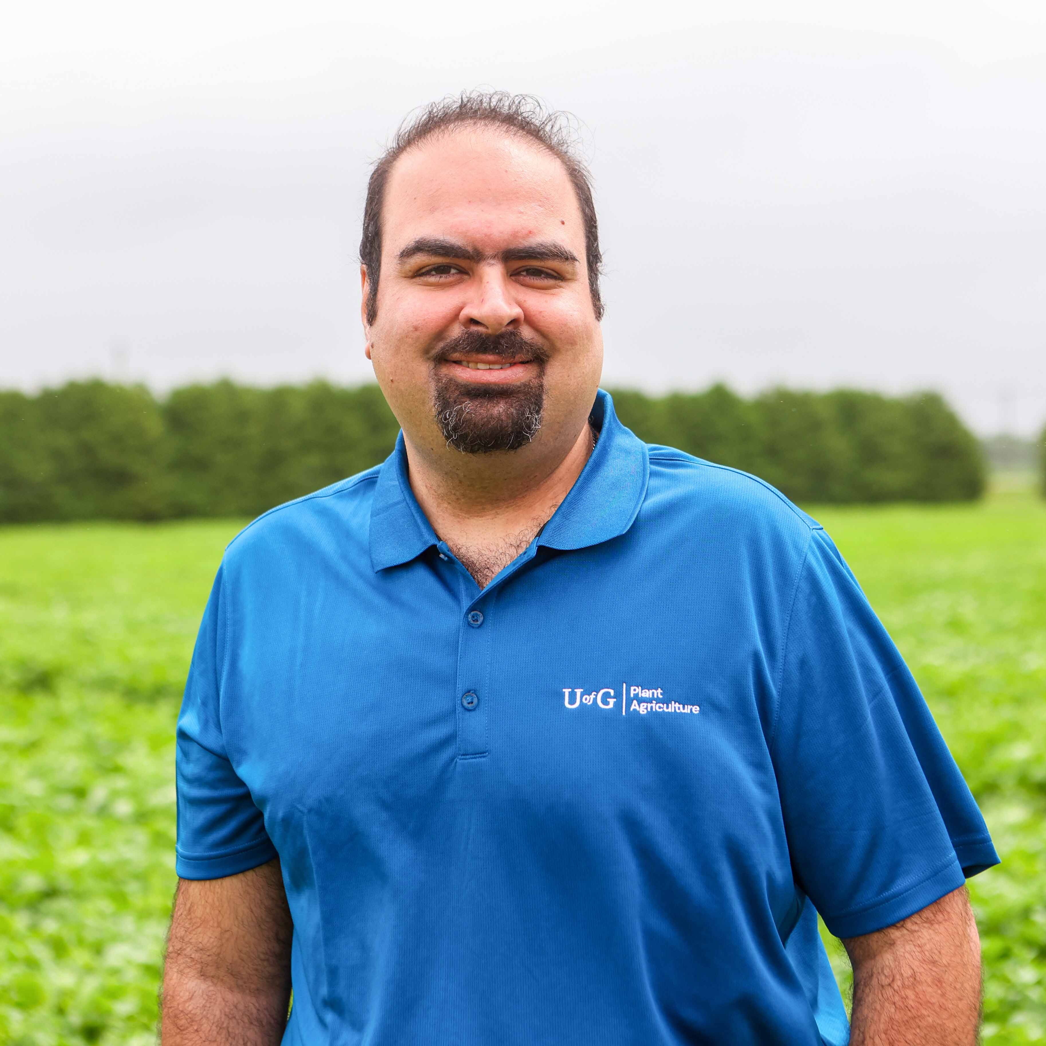 person in polo shirt poses for headshot in farmer's field