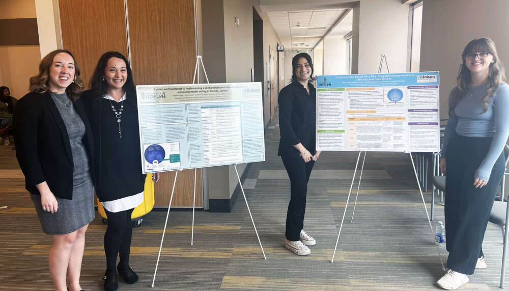 four people stand near two research posters on easels