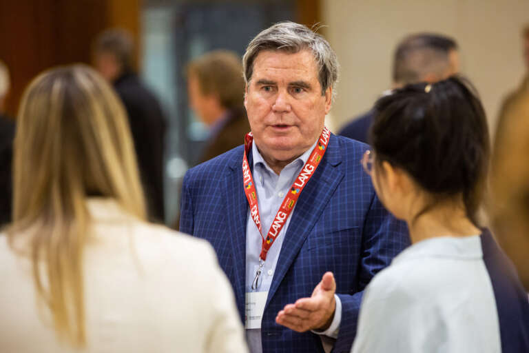 a man in a blue suit jacket speaks to two students