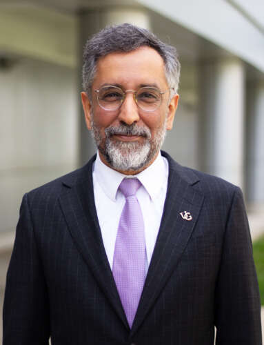 a person in a suit jacket poses for a photo outside a grey building