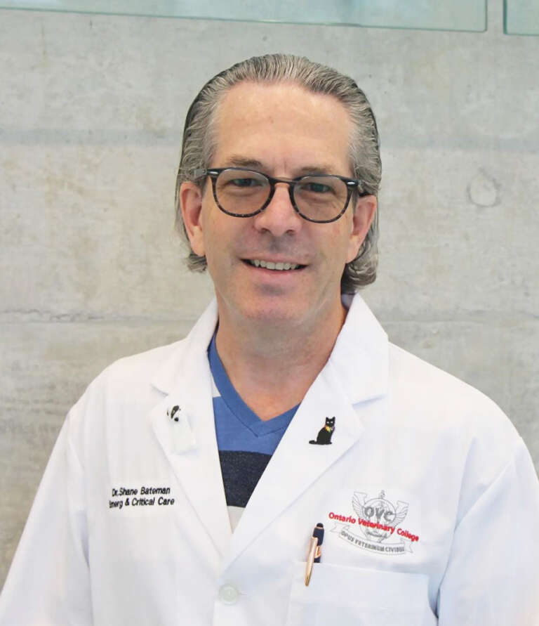 A veterinarian in a white lab coat poses for a photo