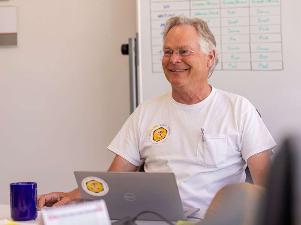 person in white shirt sits in front of grey laptop