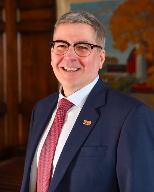 a man in a sit smiles for a portrait